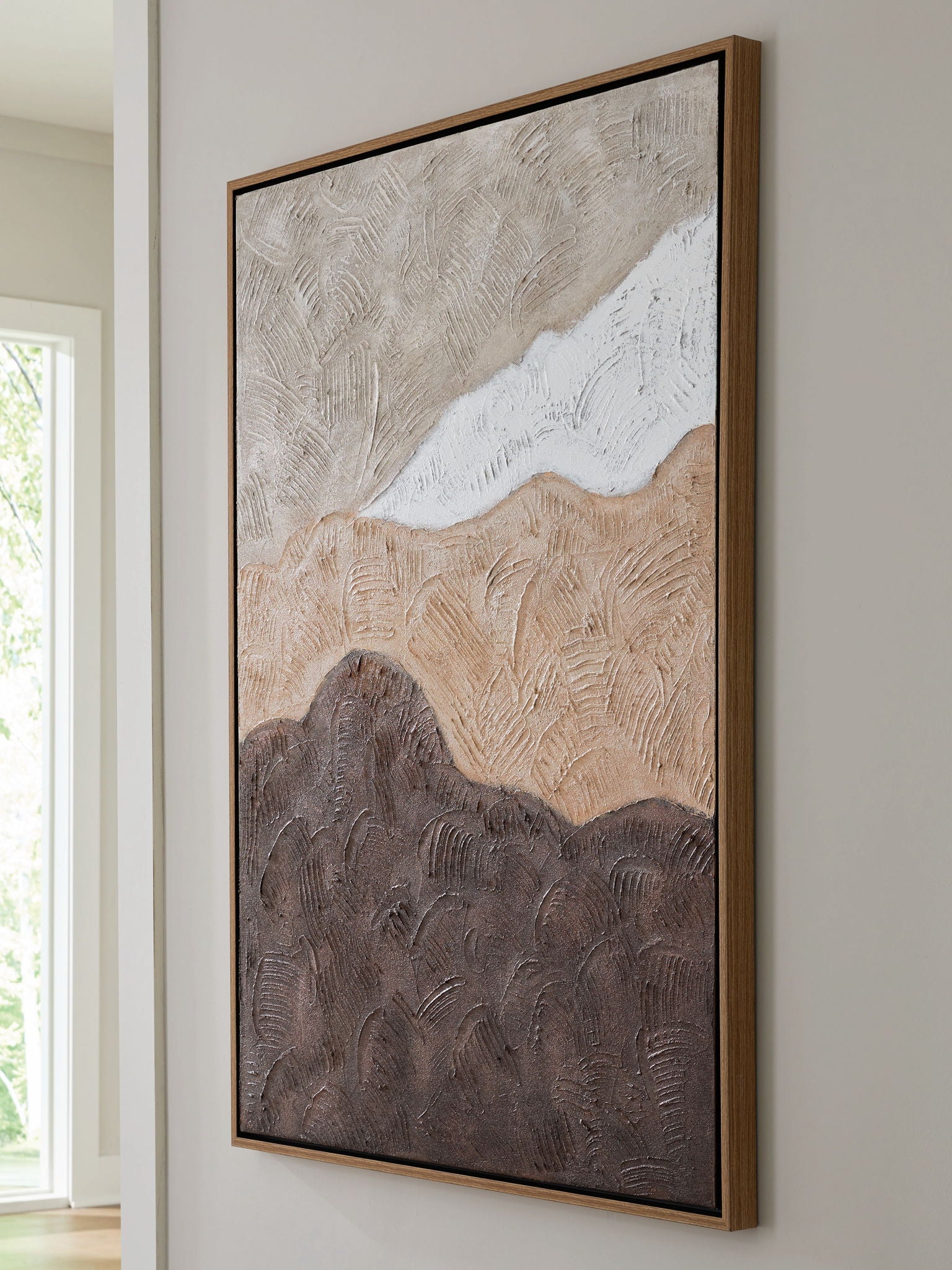 Framed abstract wall art hanging on wall, tan and white swirls over dark brown base