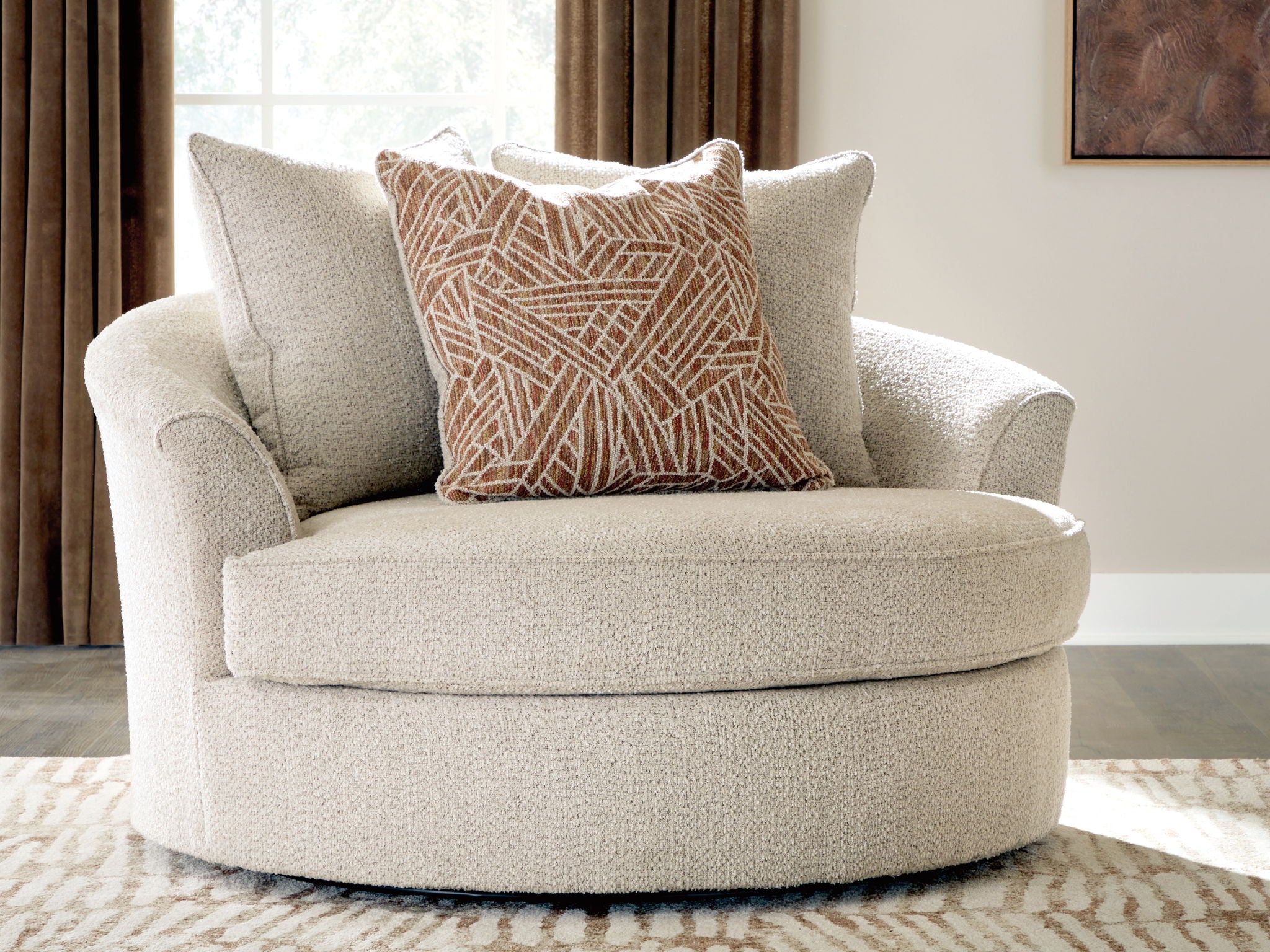 Oversized swivel accent chair in light beige with patterned lumbar pillow and two back pillows