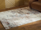 Abstract area rug in beige and gray with rust speckles