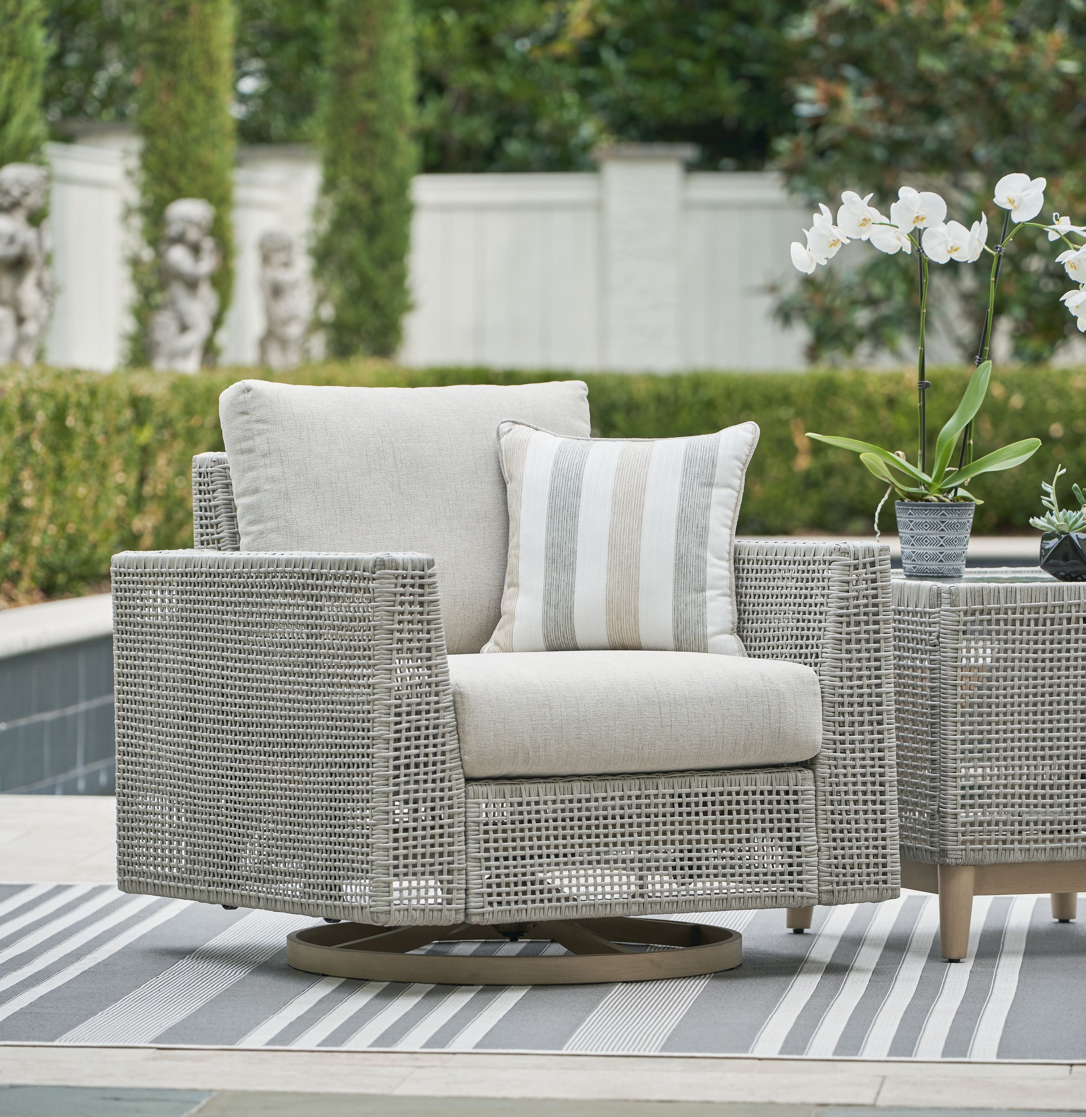 Gray swivel lounge chair with woven frame, light cushion, and striped throw pillow