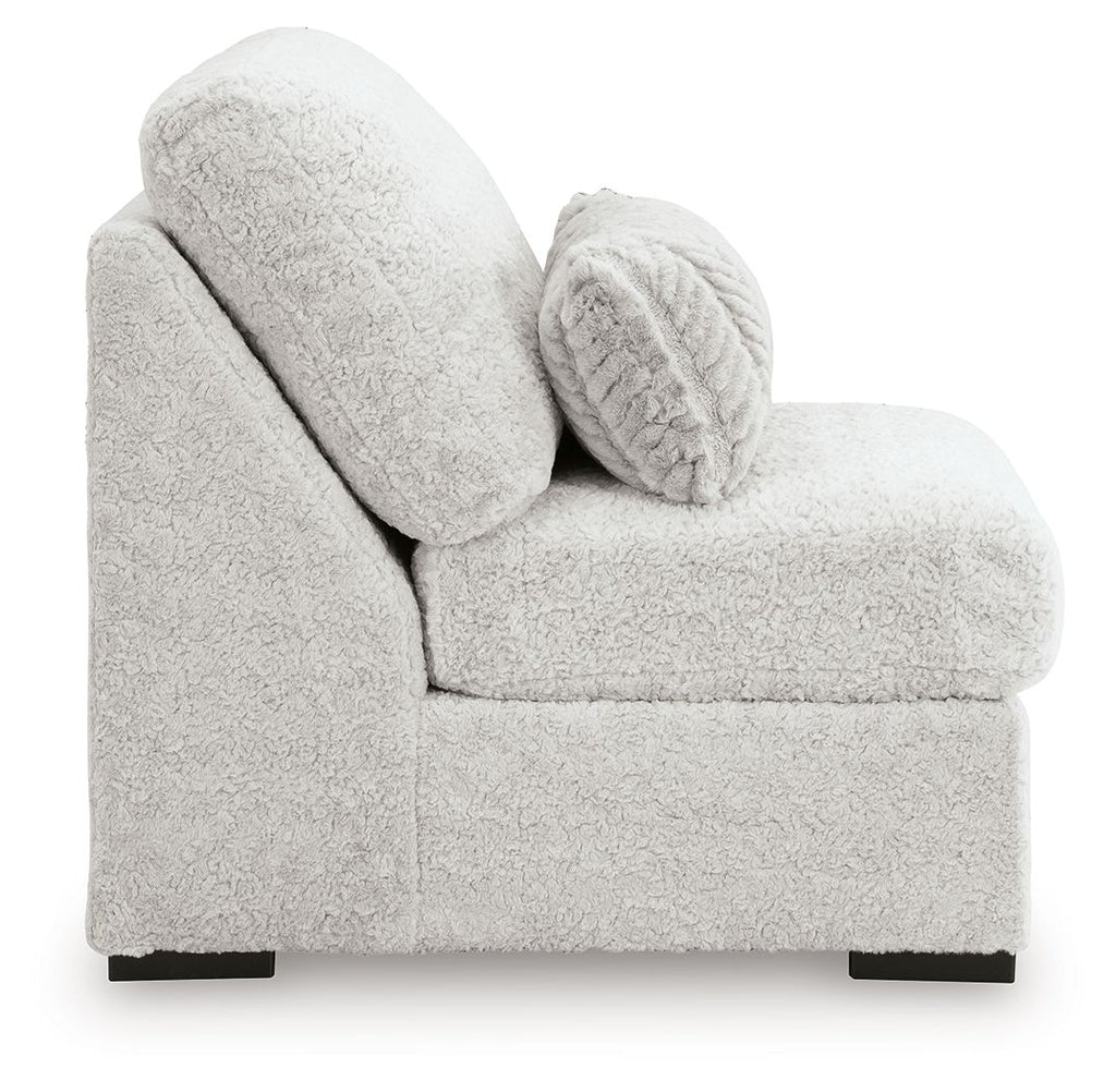 Light gray armless chair with rounded arms, plush seat, and patterned lumbar pillow