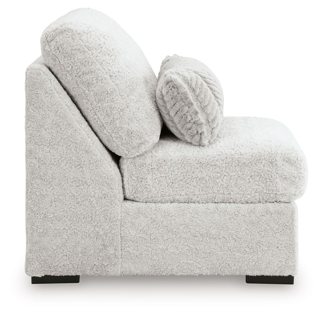 Light gray armless chair with rounded arms, plush seat, and patterned lumbar pillow