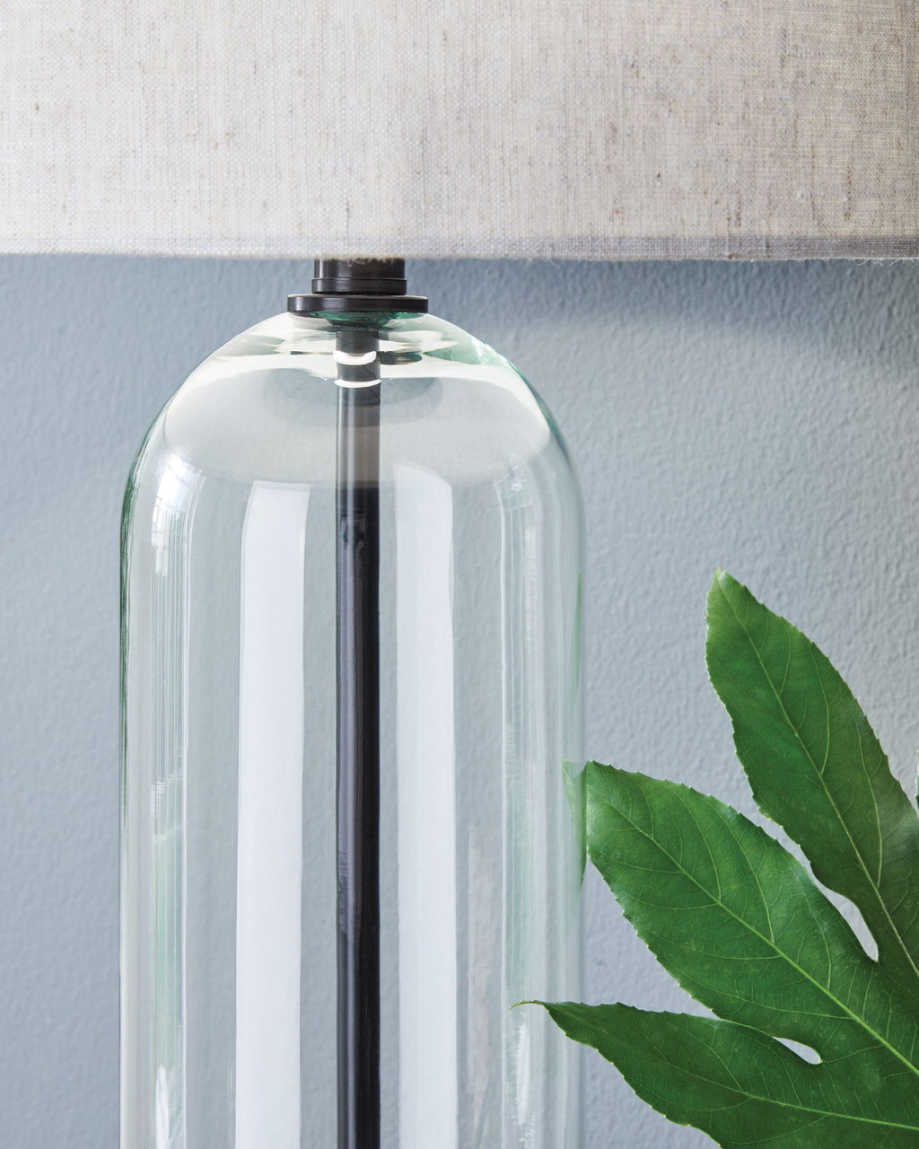 Clear glass lamp body with black metal stem and fabric drum shade
