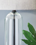 Clear glass lamp body with black metal stem and fabric drum shade