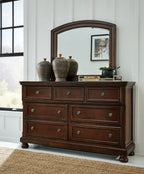 Dark brown dresser with arched mirror and six drawers with round metal knobs