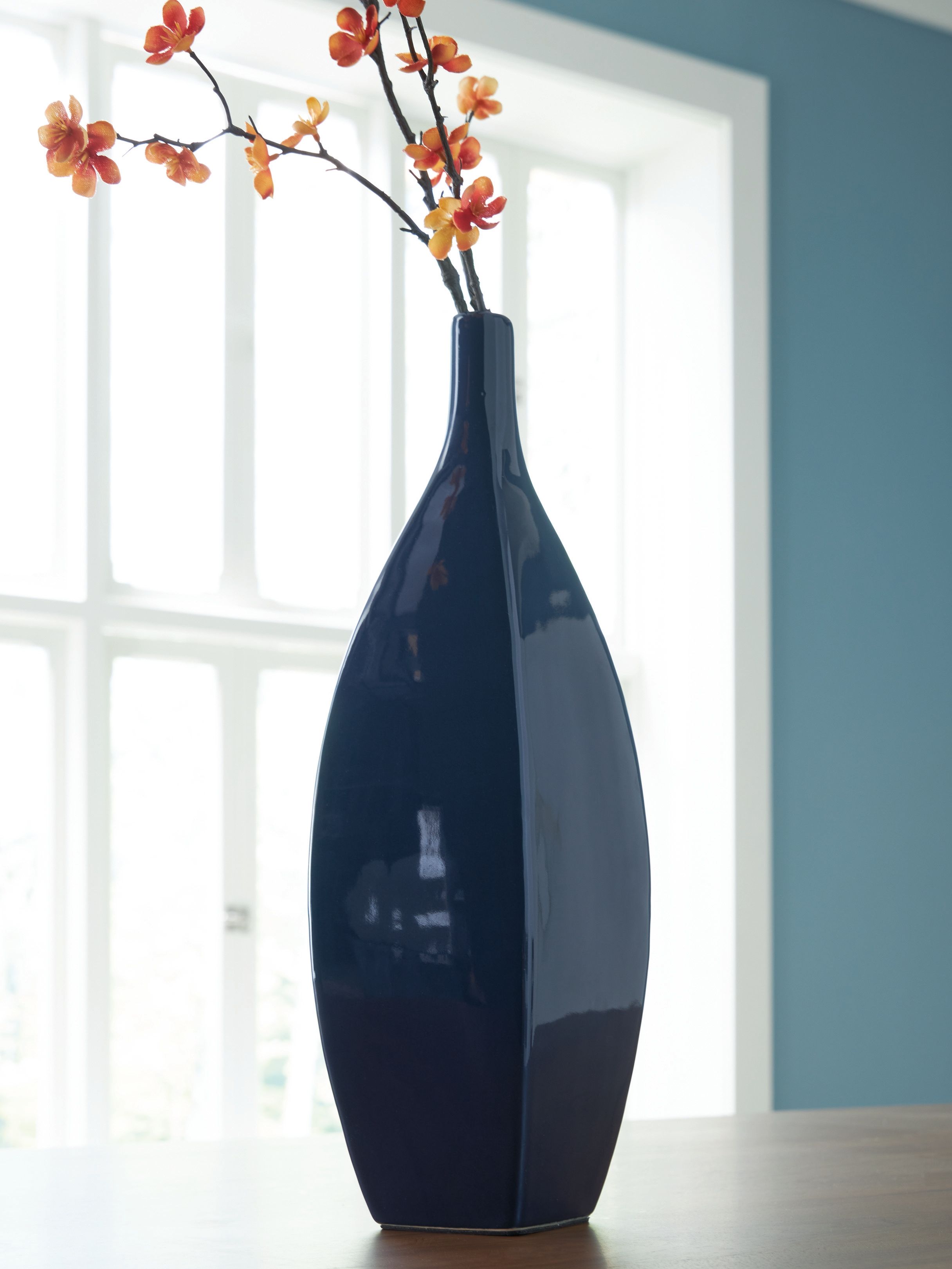 Glazed blue ceramic vase with narrow neck and blooming branches