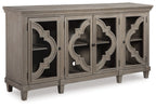 Gray accent cabinet with four doors, arched cutout panels, and tapered legs