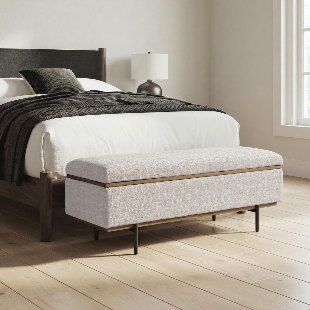 Stone upholstered storage bench with hinged top and dark metal legs