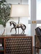 Table lamp with bronze horse base and off-white fabric shade, shown on tabletop.