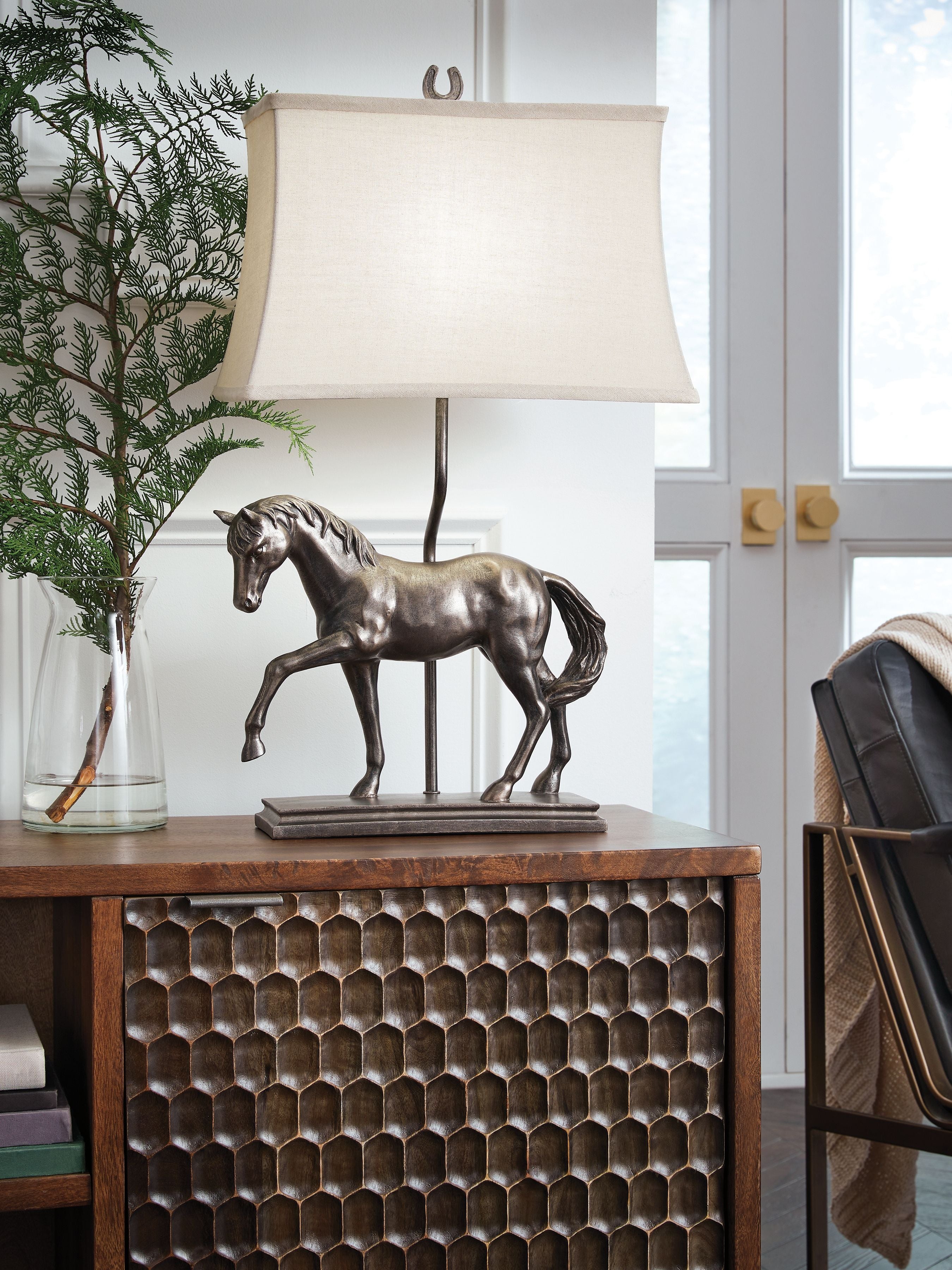 Table lamp with bronze horse base and off-white fabric shade, shown on tabletop.