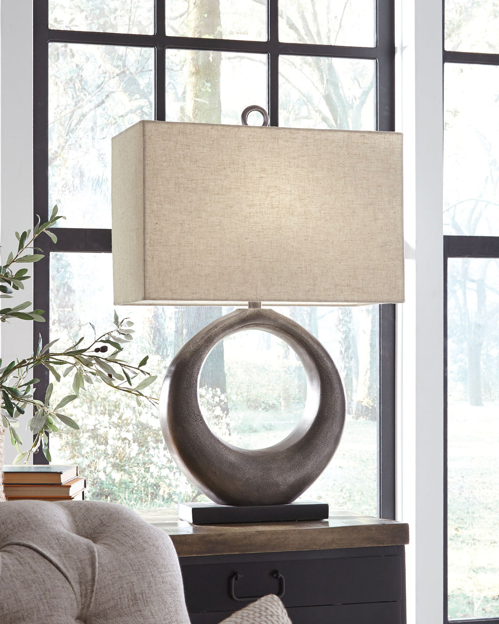 Metal table lamp with antique silver circular base and beige drum shade on stand