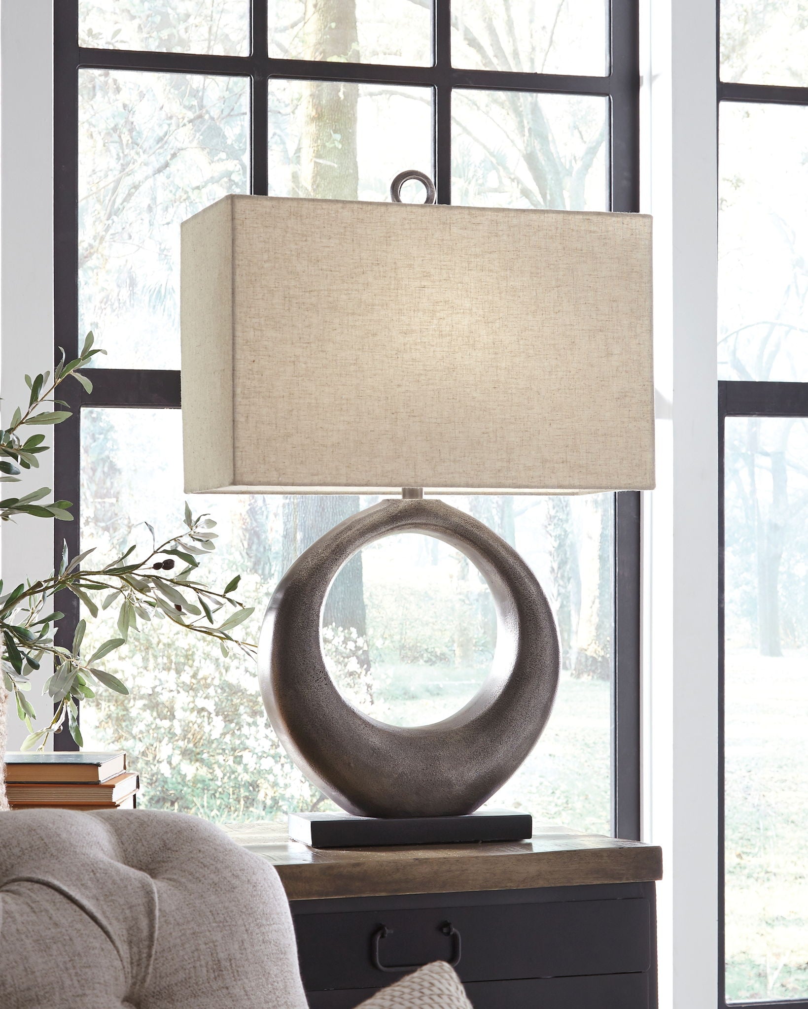 Metal table lamp with antique silver circular base and beige drum shade on stand