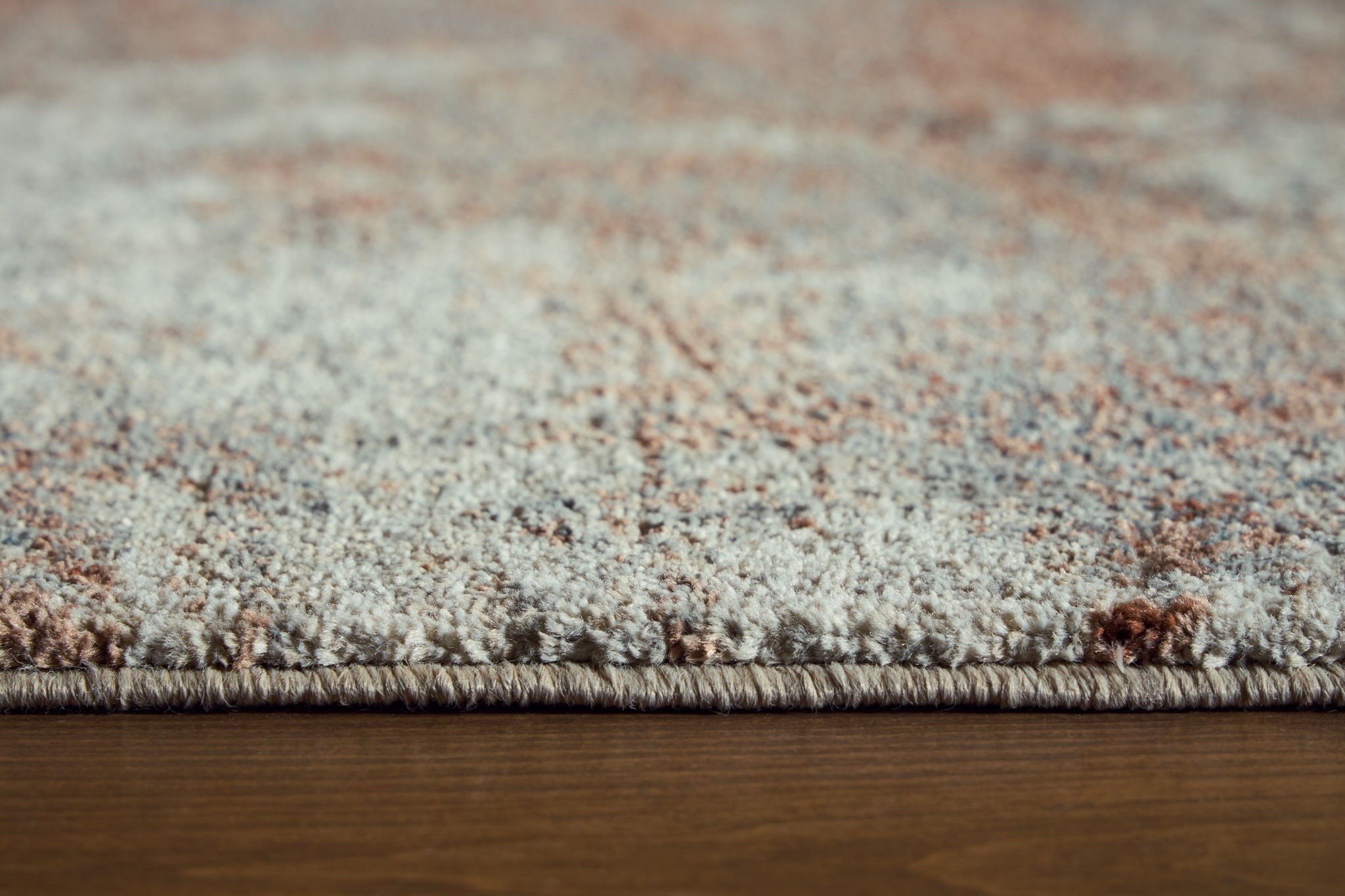Close-up of rug fibers on a beige and gray distressed abstract pattern