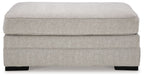 Light gray upholstered ottoman with wide padded top and black block feet