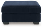 Blue ottoman with ribbed fabric, rounded padded top, dark legs.