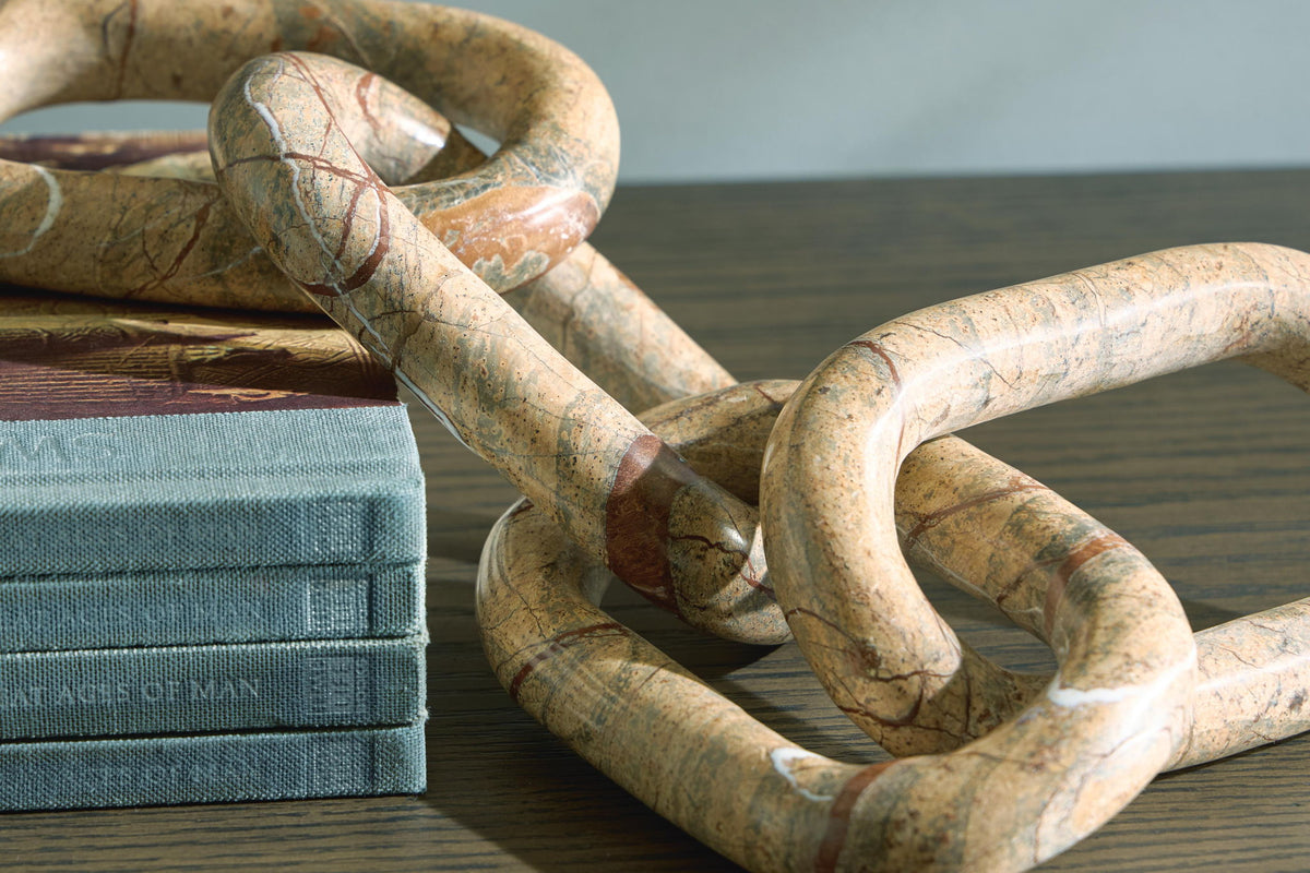 Light brown marble-look chain link sculpture with interlocking rings beside books