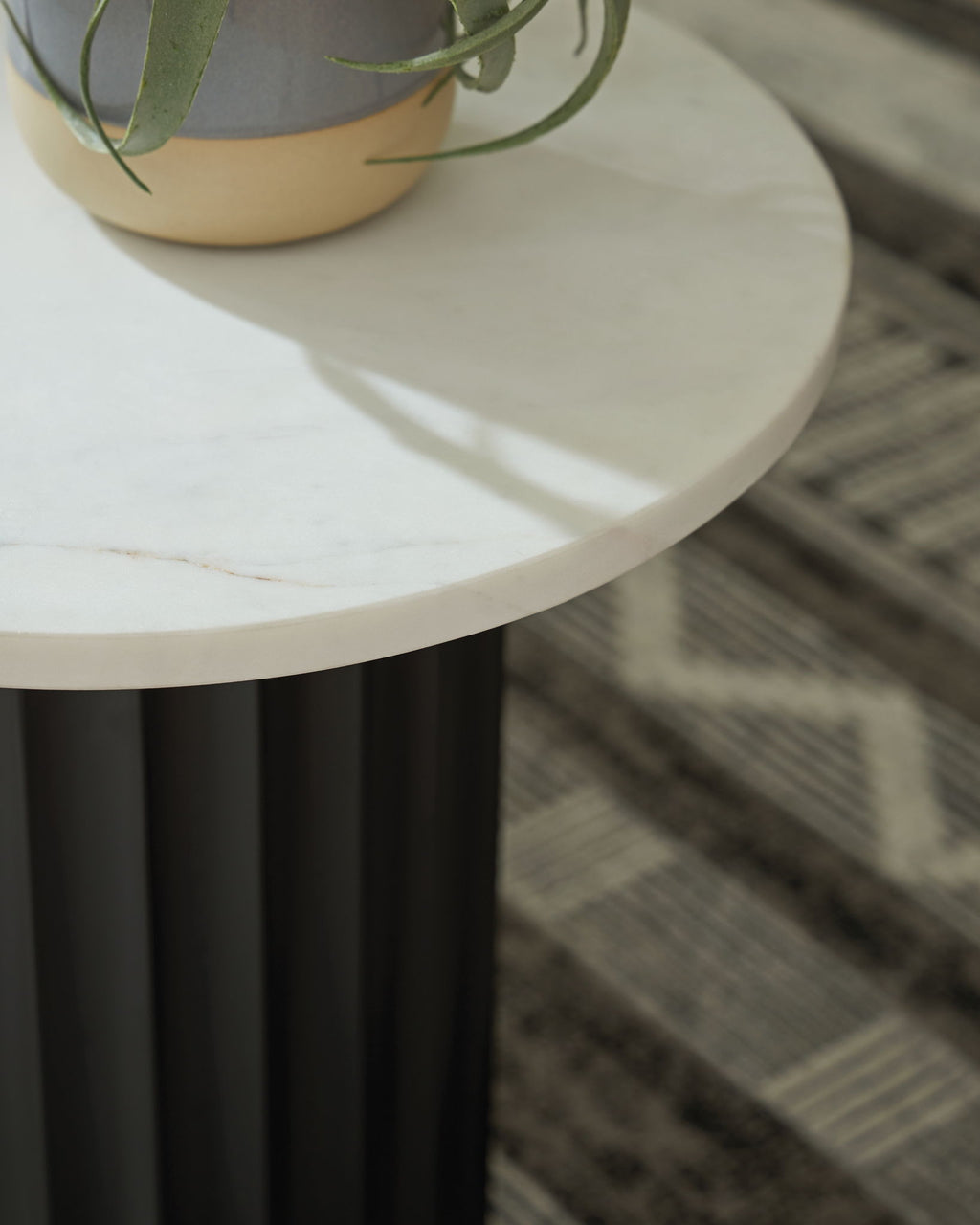 White tabletop edge and black fluted pedestal with small plant pot