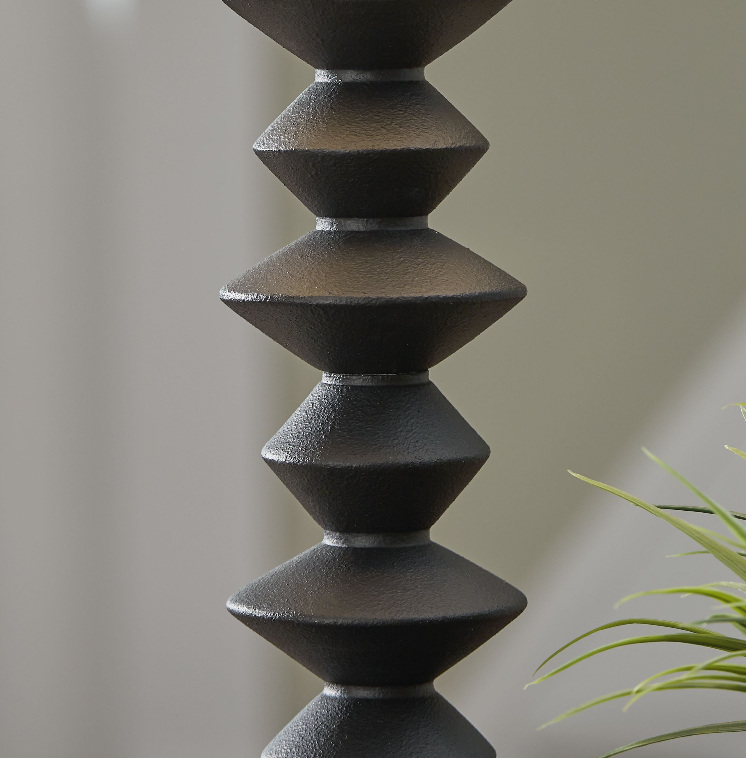 Black stacked geometric lamp base detail with brushed texture