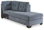 Blue denim corner chaise with tufted back and padded arms on dark legs
