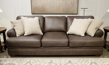 Dark brown fabric sofa with three cushions and four beige throw pillows