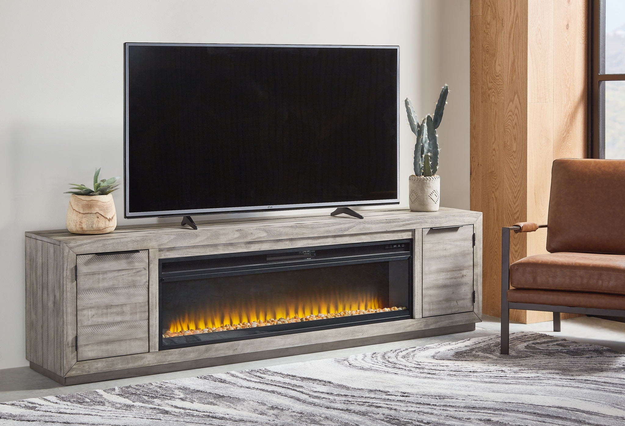 Gray TV stand with wide fireplace insert and two side cabinet doors, TV on top