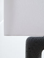 Light fabric lampshade edge over black textured lamp base