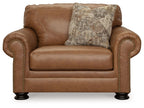 Caramel chair and a half with rolled arms, nailhead trim, and square patterned pillow