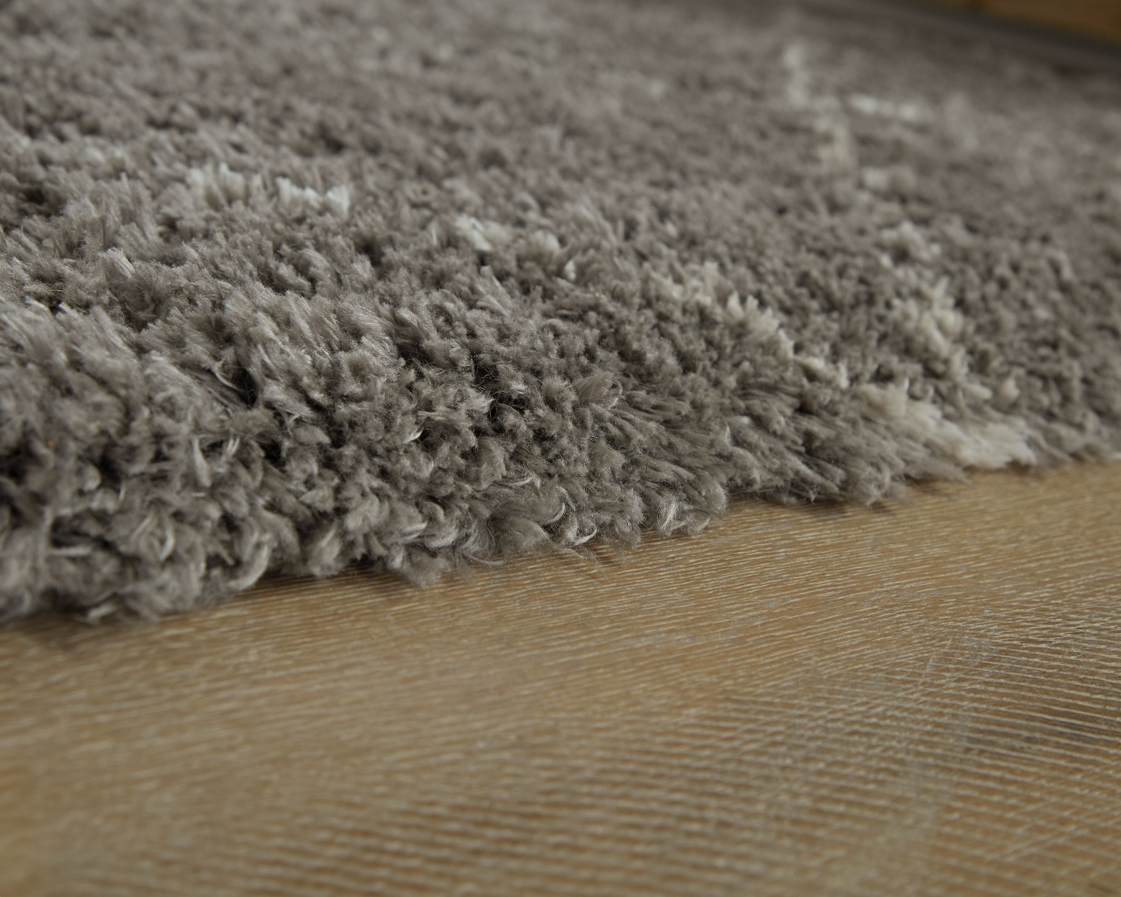 Dark gray shag area rug edge close-up with dense, textured pile
