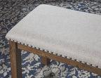 Beige upholstered bench edge with dark nailhead trim and button tufting