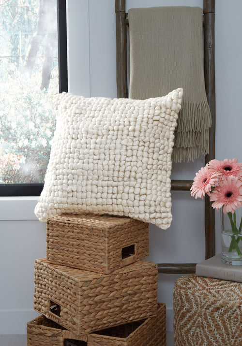 Woven textured pillow with pom-pom loops and short fringe on one side