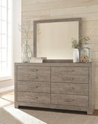 Gray dresser with rectangular mirror and six drawers with horizontal metal pulls.