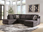 Dark charcoal fabric sectional sofa with chaise and three patterned throw pillows on cushions