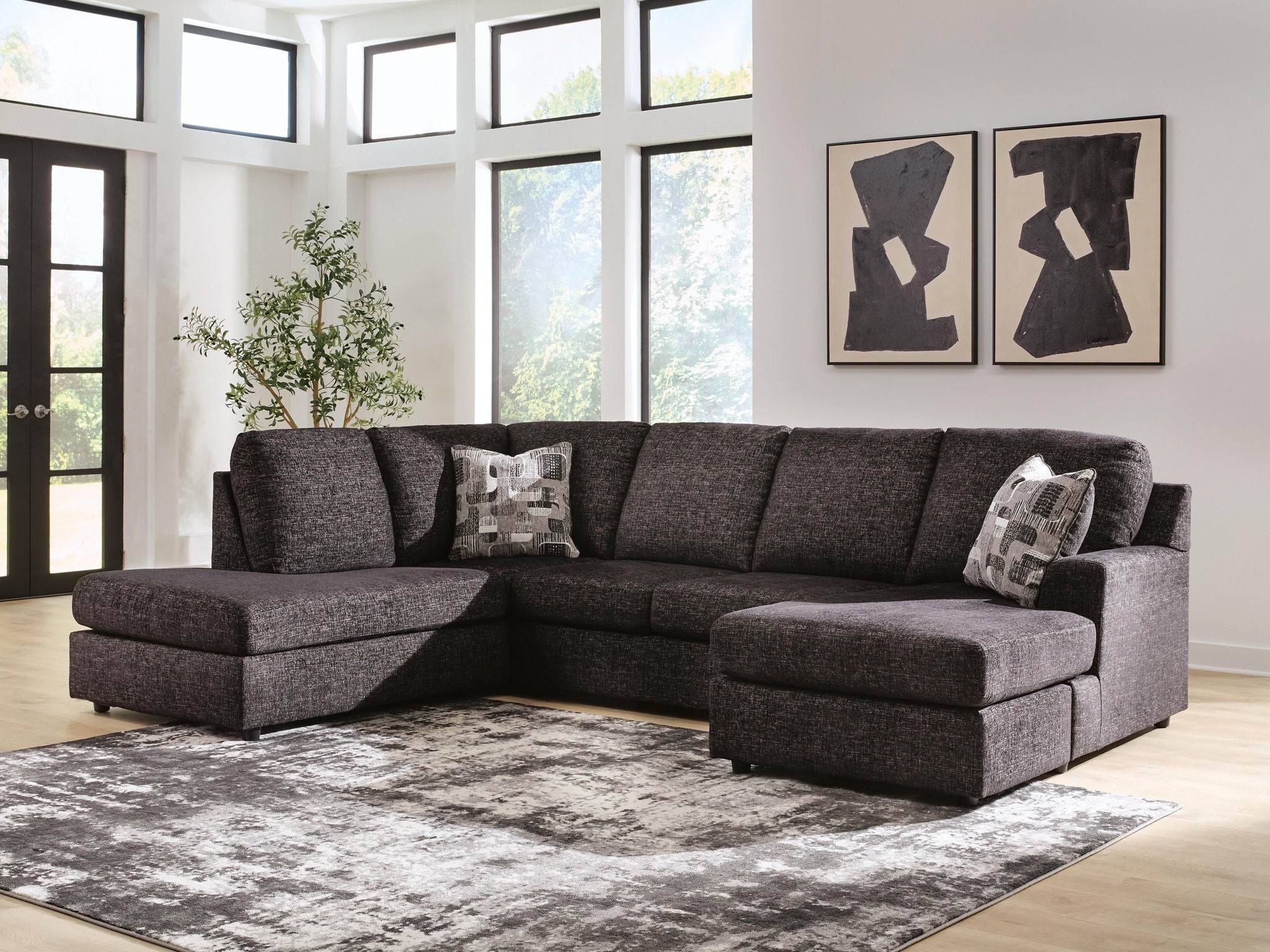 Dark charcoal fabric sectional sofa with chaise and three patterned throw pillows on cushions