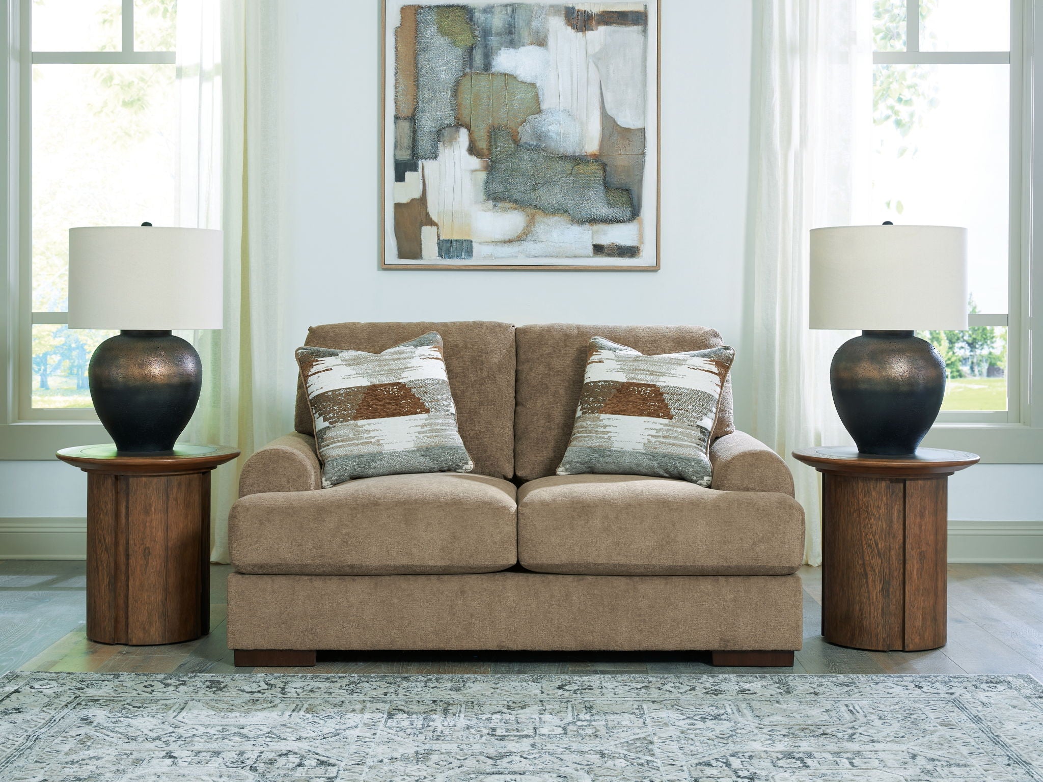 Beige loveseat sofa with two seat cushions and patterned accent pillows, square arms