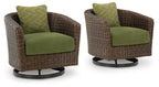Brown woven wicker swivel lounge chair with green seat cushion and patterned back pillow