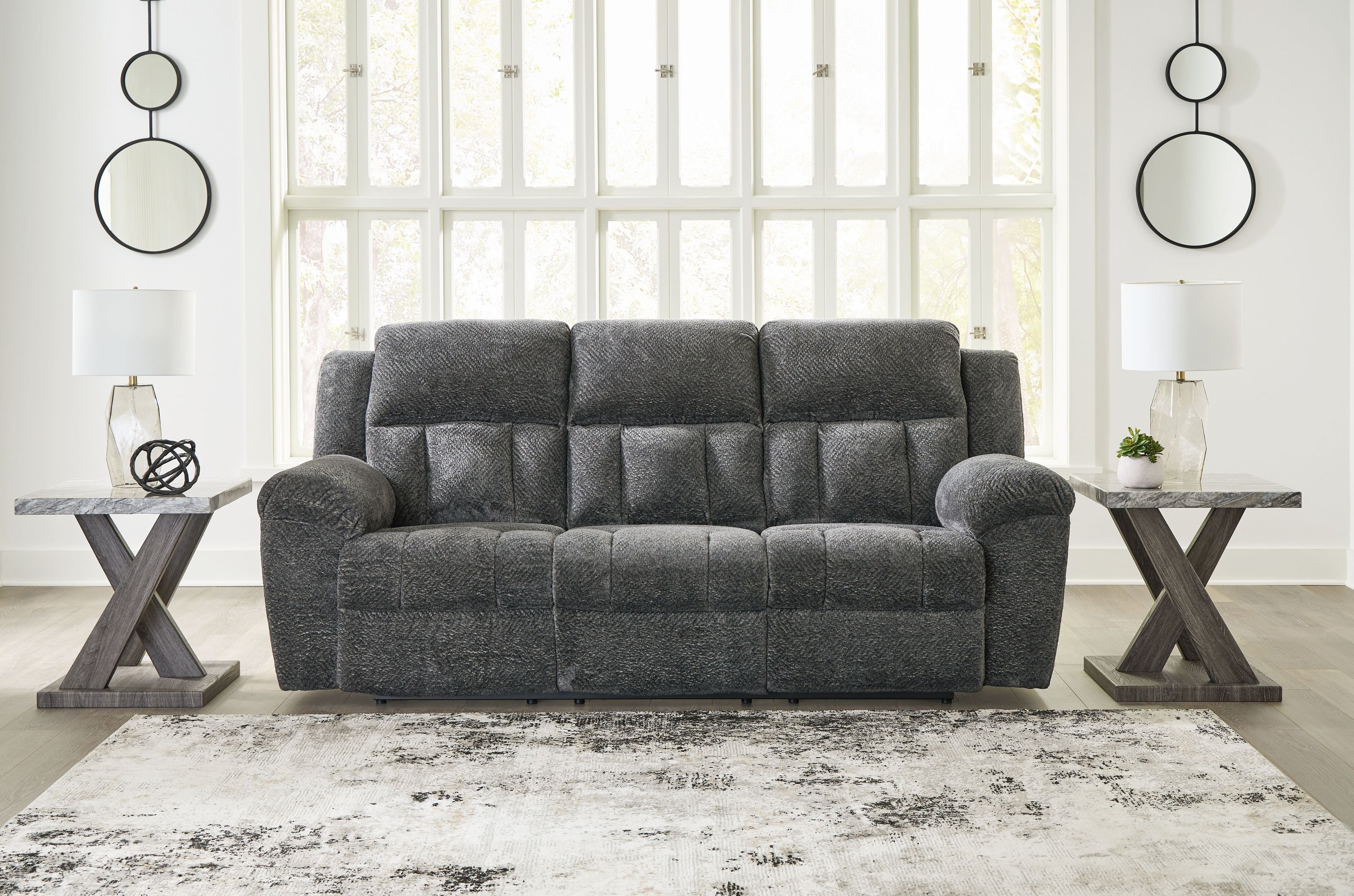 Graphite gray reclining sofa with tufted cushions, rounded arms, and centered seat back