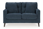 Blue loveseat with tufted back and two padded seat cushions with rolled arms.