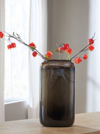 Sumner vase with dark brown glossy glass and red flower stems arranged in it