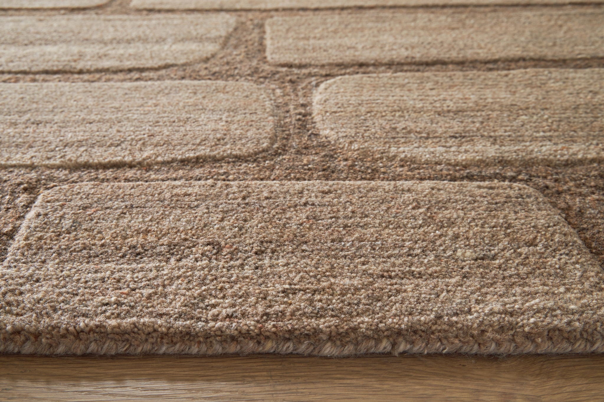 Brown and beige textured rug pile with stitched edge binding
