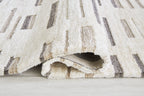 Pearl silver rug corner with textured edge and dark gray stripe motif