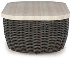 Beige tabletop on dark brown wicker cocktail table with rounded corners