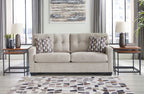 Light gray fabric sofa with two square patterned pillows and tufted back cushions
