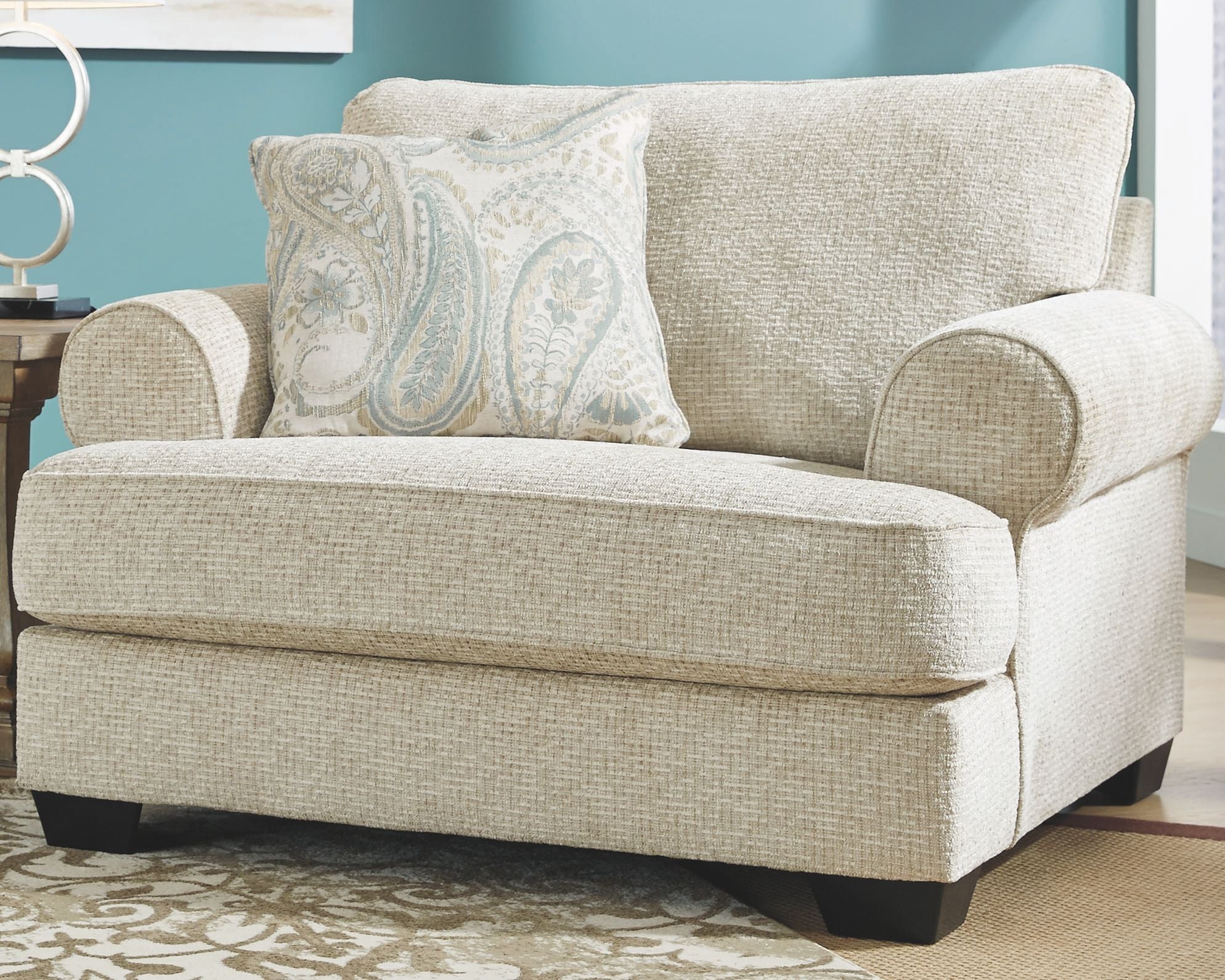 Sandstone chair and a half upholstered in light textured fabric, with rolled arms and pillow