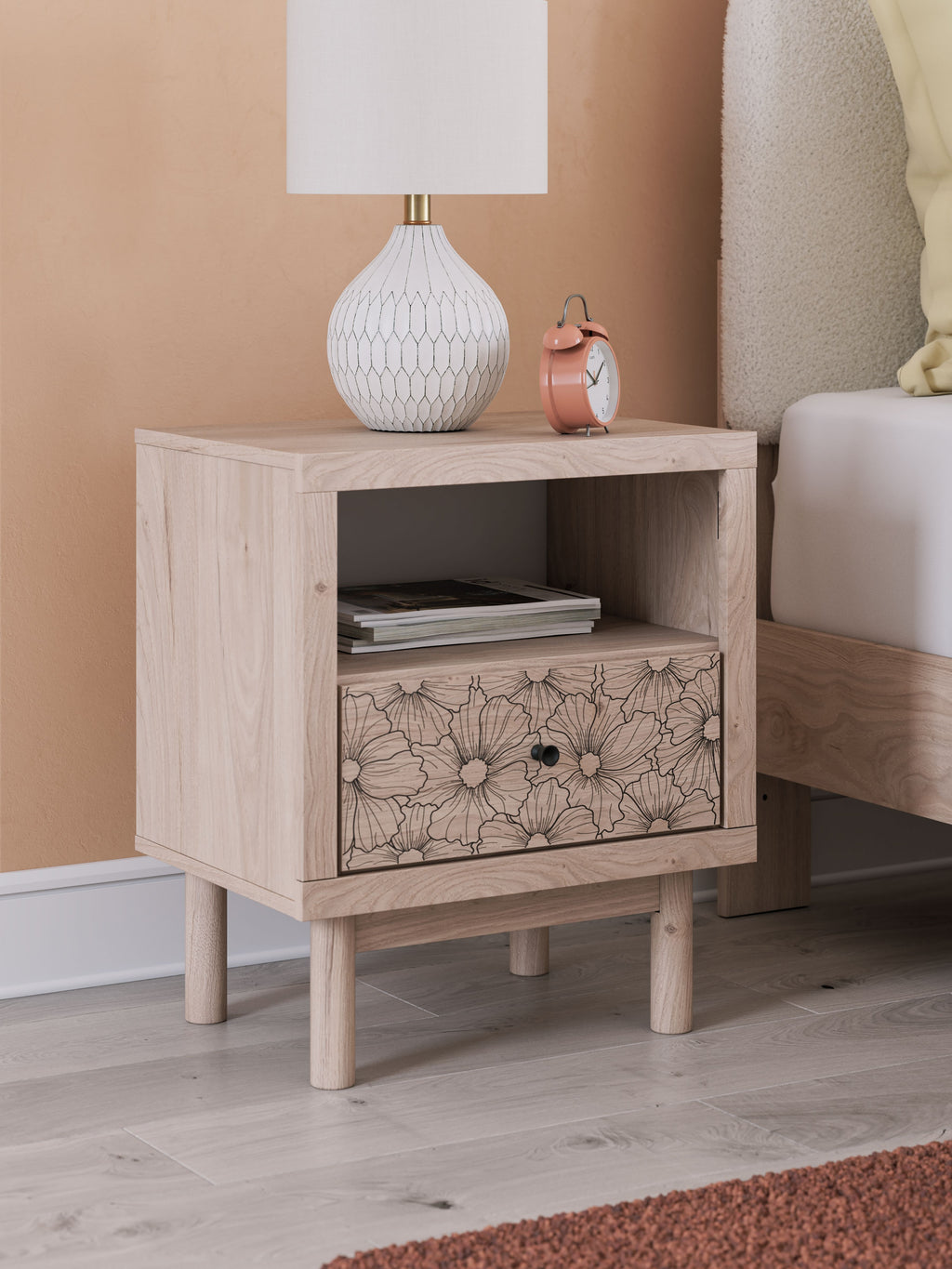 Tan wood night stand with open shelf and floral drawer front, mounted feet