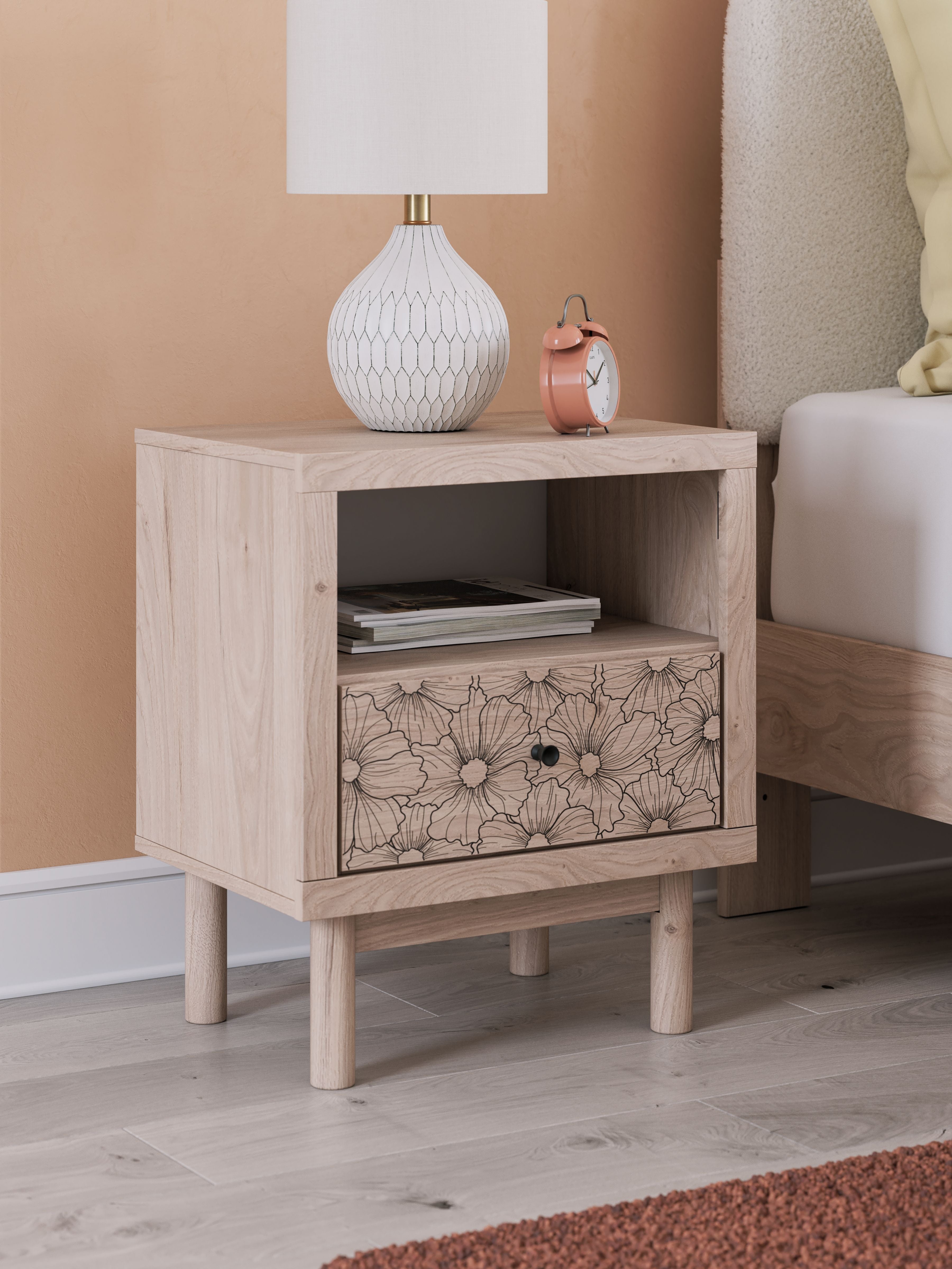 Tan wood night stand with open shelf and floral drawer front, mounted feet