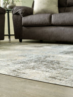 Washable area rug with low-pile beige and gray abstract pattern on light flooring