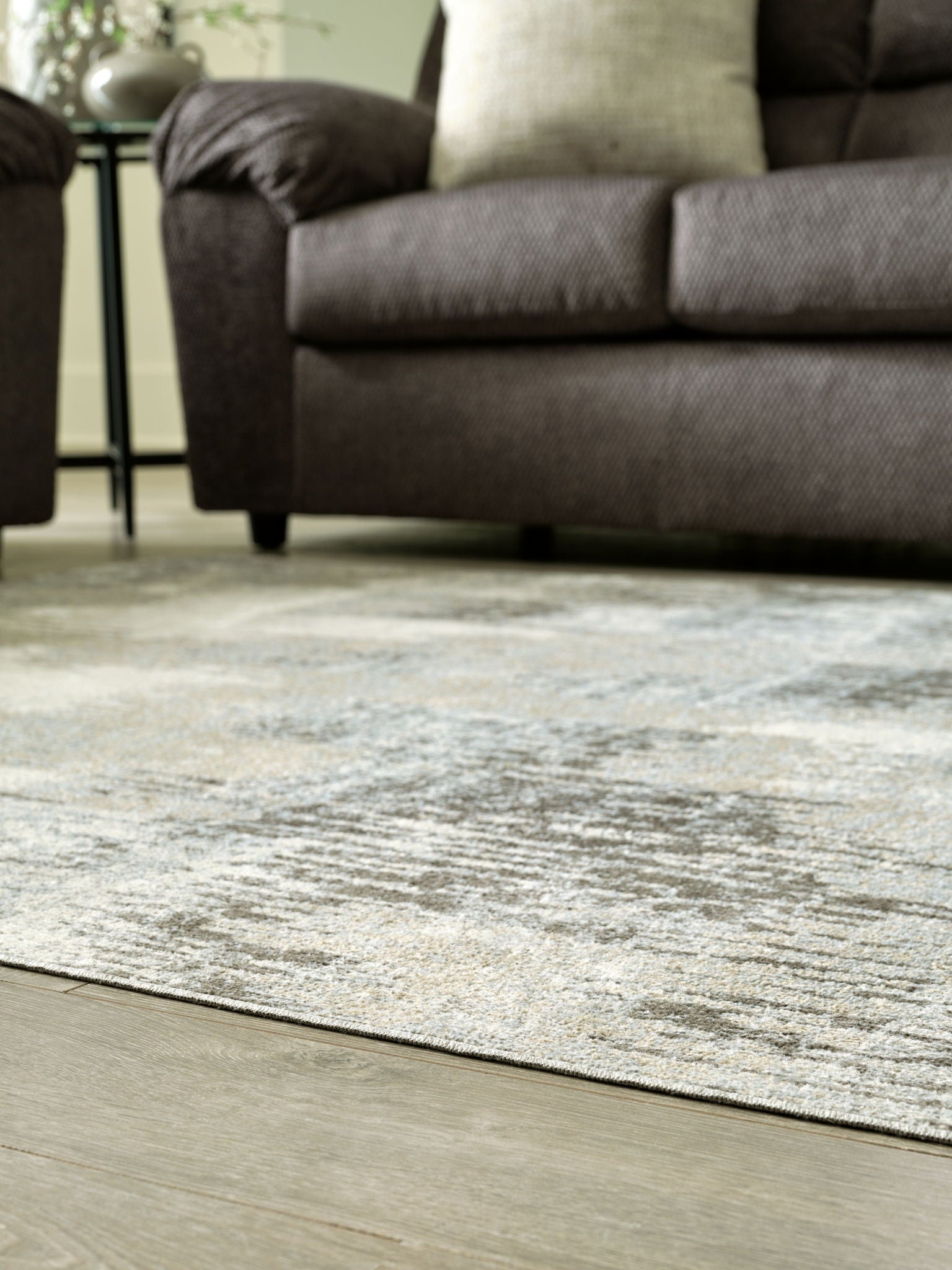 Washable area rug with low-pile beige and gray abstract pattern on light flooring