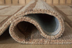 Rolled rug edge showing short pile and backing fabric in brown and tan