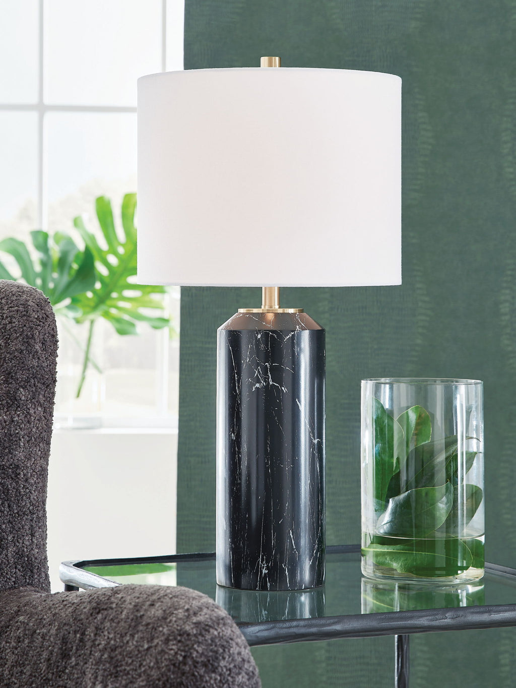 Black table lamp with white drum shade and gold hardware on black marble column