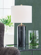 Black table lamp with white drum shade and gold hardware on black marble column